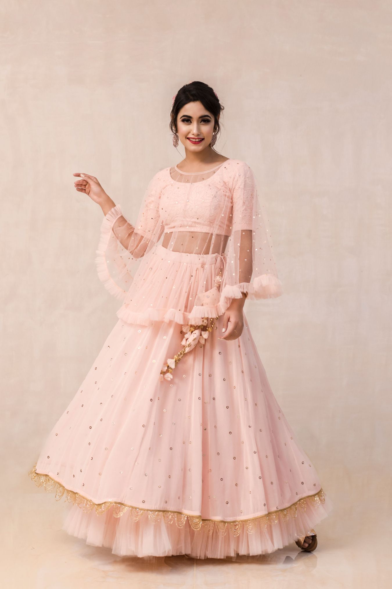 Vivacious Georgette Lehenga Paired with Handcrafted Chikan Blouse Embellished with Mukaish Rings All Over in Blooming Peach Color. Delicately Falling Sheer Cape with Frills for Accentuating the Style of the Whole Outfit